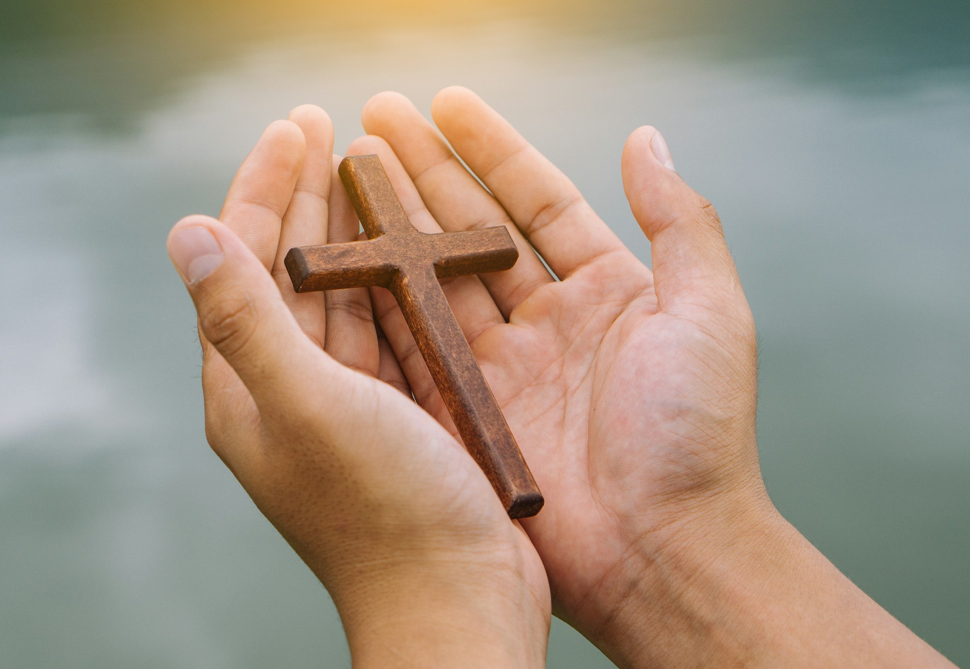 the man praying with cross in river background, Symbol of Faith.